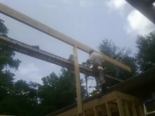 Carpenter setting a ridge beam over a new addition frame — Ice Dam Removal by Roofing Brothers in Blue Creek