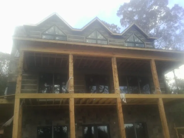 Dormers and porch framing on a large log home under construction — Roof Coating work by our crew in Blue Creek