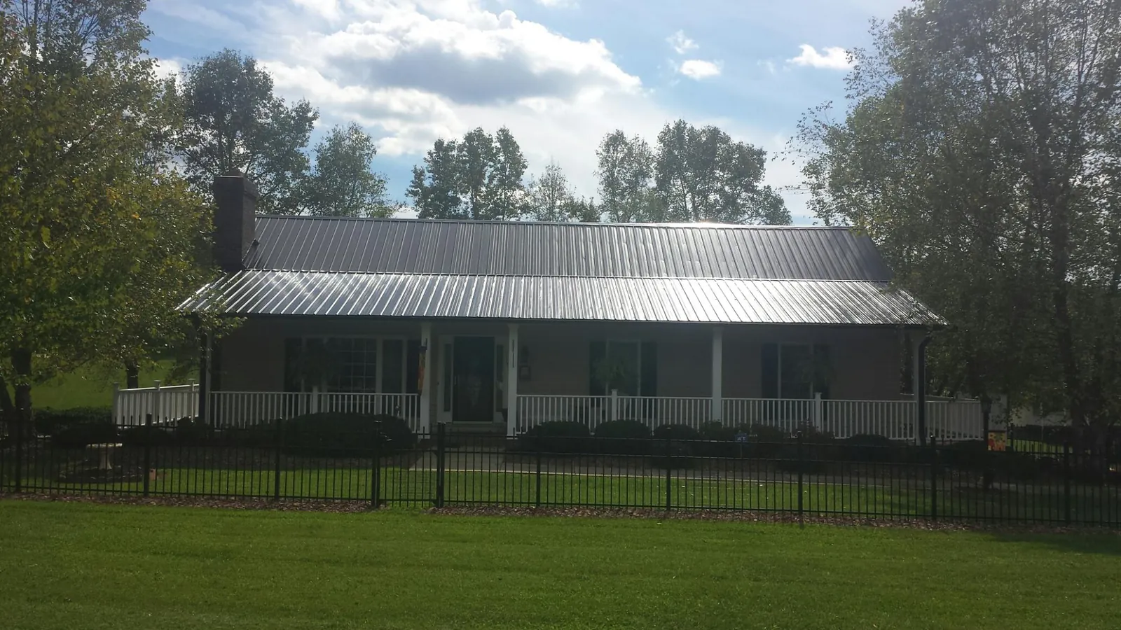 Gray metal roof on a brick ranch with a full width front porch — Gutter Guard Installation work by our crew in Blue Creek
