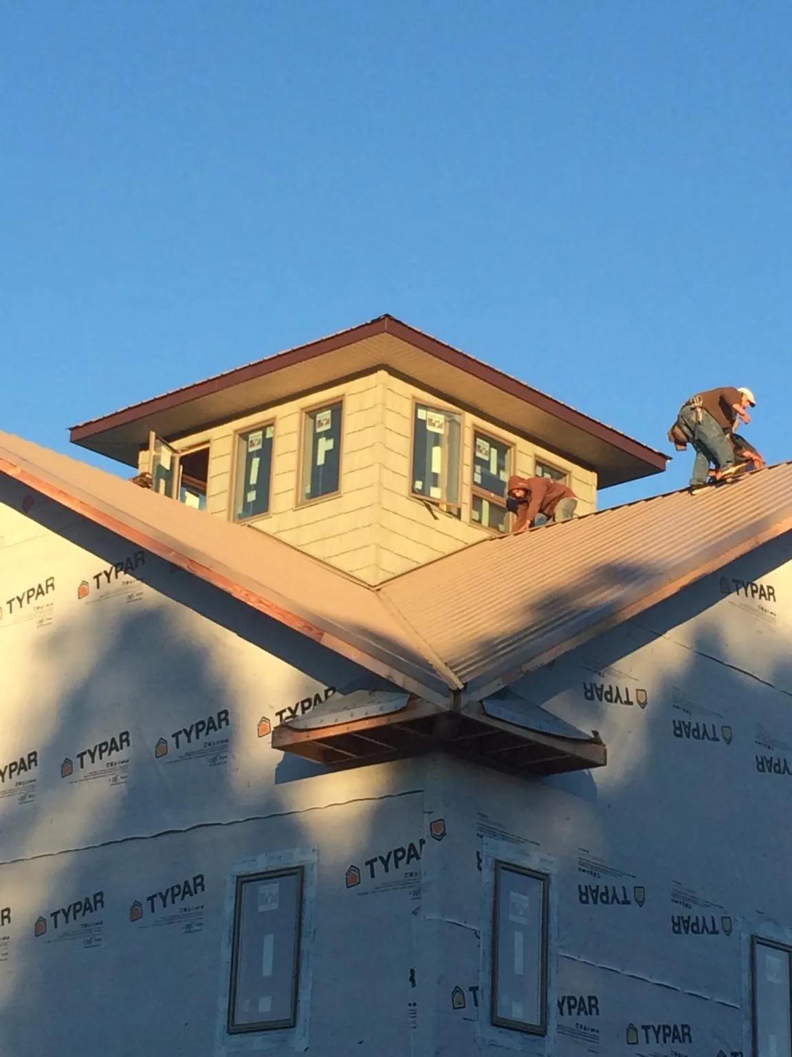 Roofers working around a rooftop cupola on a new metal roof at sunset — Roof Waterproofing in Blue Creek by Roofing Brothers